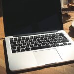 Notebook com website na tela e anotações de planejamento sobre mesa de trabalho