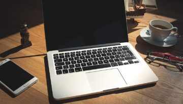 Notebook com website na tela e anotações de planejamento sobre mesa de trabalho
