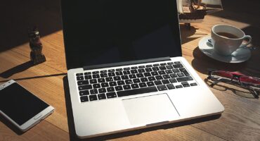 Notebook com website na tela e anotações de planejamento sobre mesa de trabalho