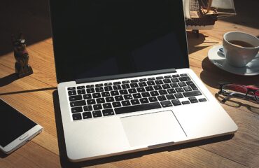 Notebook com website na tela e anotações de planejamento sobre mesa de trabalho